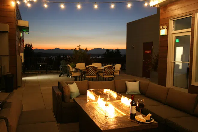 Rooftop fire pit with lounge seating and sunset views at Admiral Station Apartments.