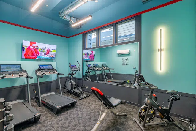 Fitness center with cardio equipment and free weights at Admiral Station Apartments.