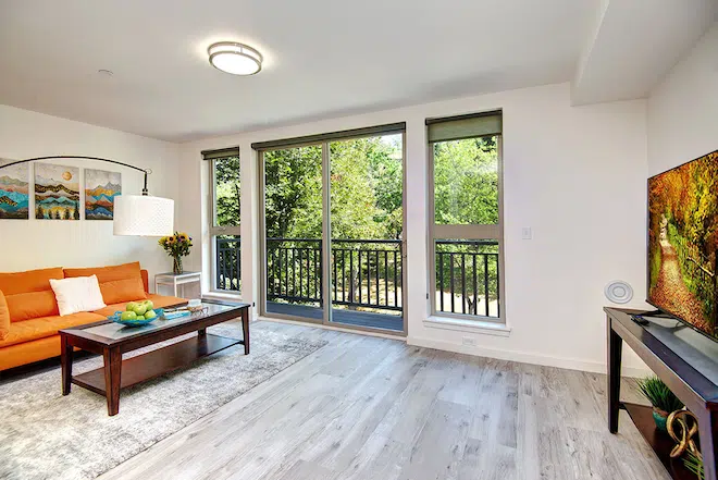 Bright apartment living room with private balcony, large windows, and open floor plan.