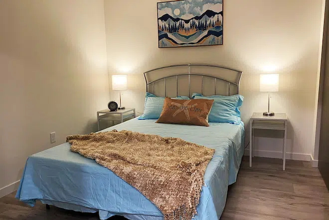 Staged apartment bedroom with large windows and contemporary finishes.